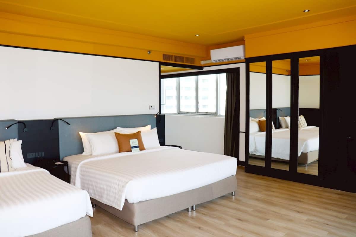 Una habitación de hotel moderna con dos camas, un espejo grande y vistas a la ciudad.