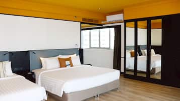 A modern hotel room with two beds, a large mirror, and a view of the city.