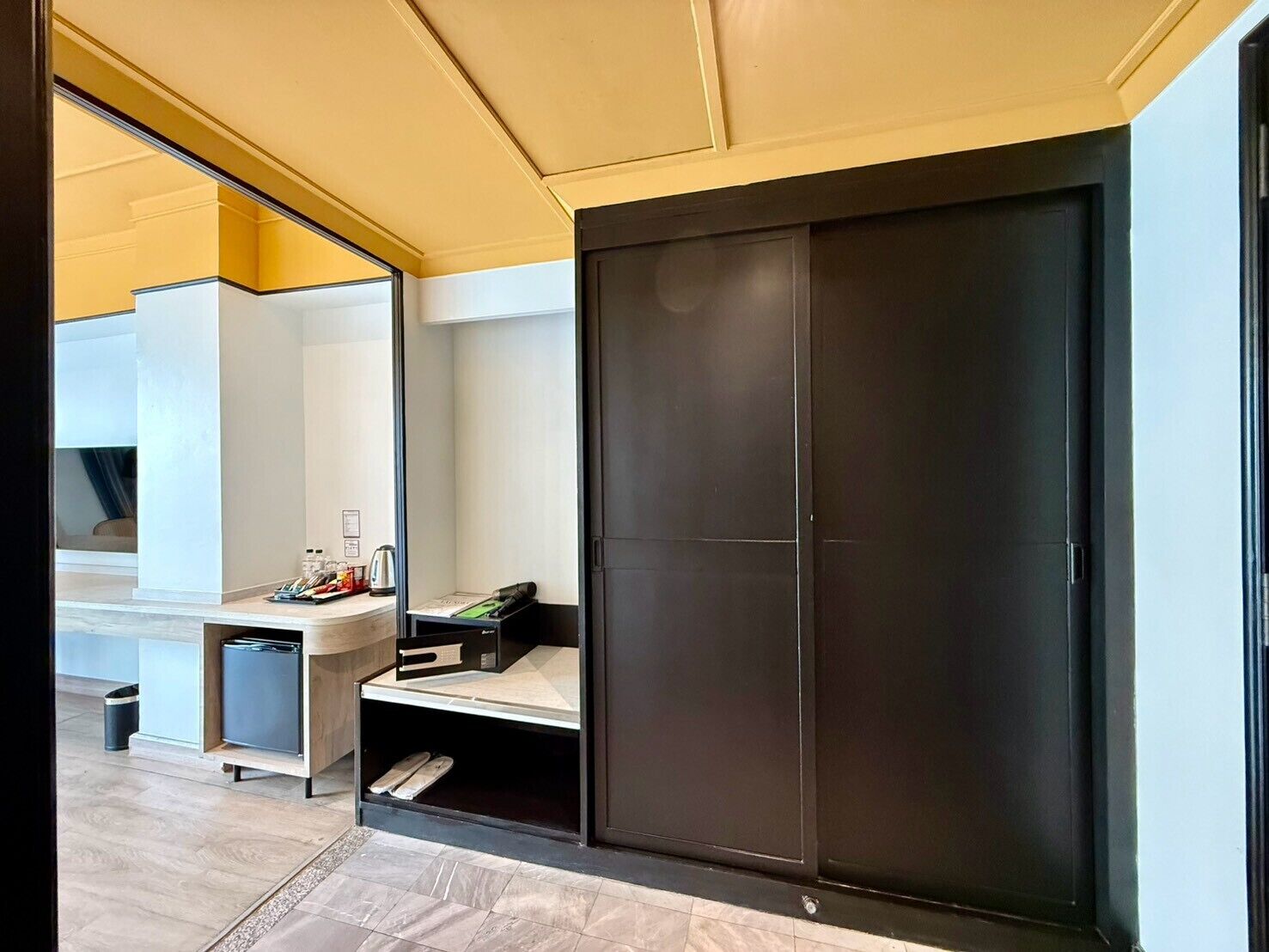 Habitació moderna amb un armari de portes corredisses, una cuineta petita i un mirall que reflecteix l'espai.