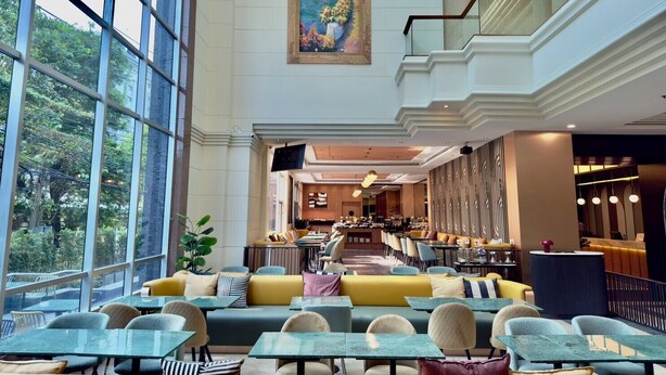 Un vaste espace intérieur doté de grandes fenêtres, un coin repas avec tables et chaises, et un bar/salon.
