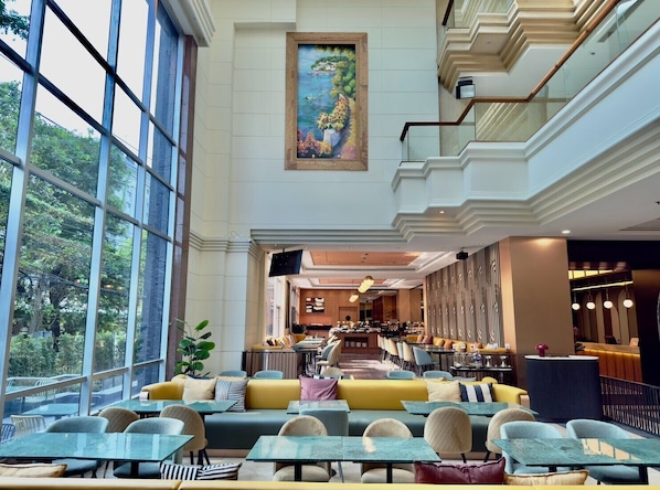 A spacious indoor area with large windows, a dining area with tables and chairs, and a bar/lounge area. - The Quarter Saphan Khwai by UHG (Bangkok)