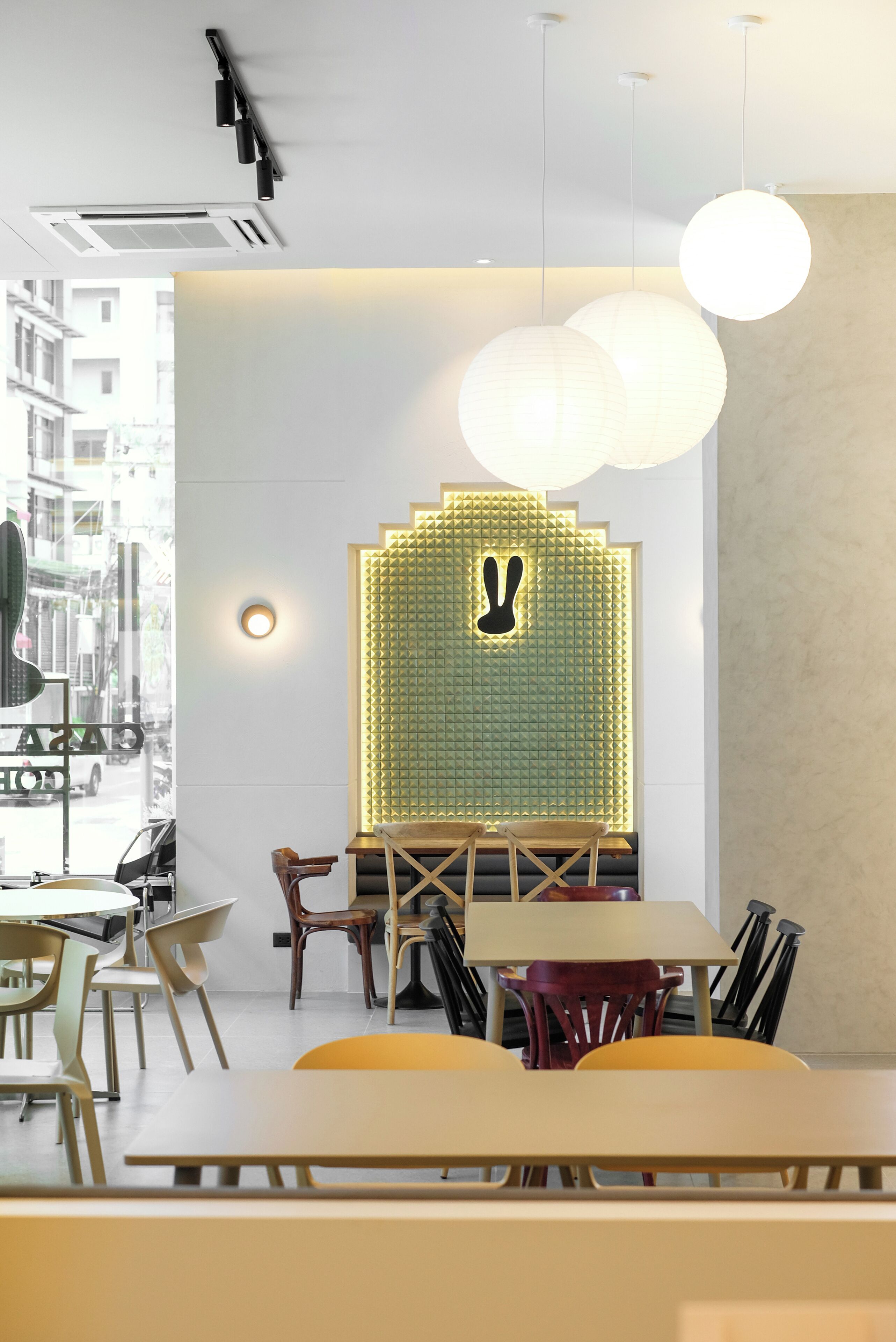 A modern restaurant interior with a central seating area, a decorative wall with a bunny silhouette, and hanging spherical lights.