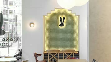 A modern restaurant interior with a central seating area, a decorative wall with a bunny silhouette, and hanging spherical lights.