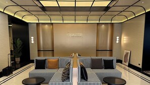 Un hall d’hôtel moderne avec un espace salon central agrémenté de canapés à rayures et de tables basses noires.