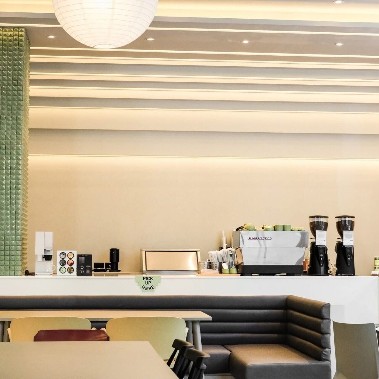 A modern cafe interior with a counter, seating area, and a coffee machine.