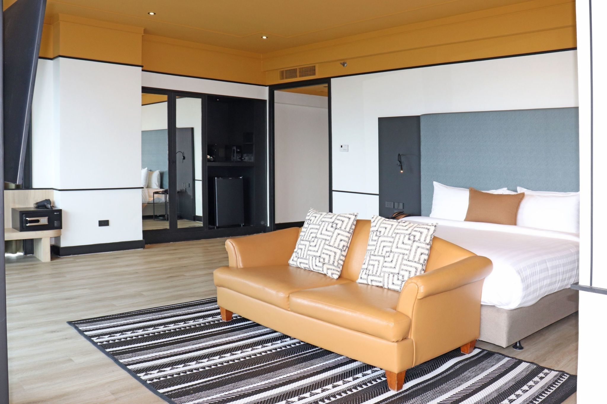 Ein modernes Hotelzimmer mit einem großen Bett, einer Couch, einem kleinen Tisch und einem Spiegel.