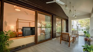 Un dormitorio moderno con televisor, cama de madera y balcón con zona de comedor.