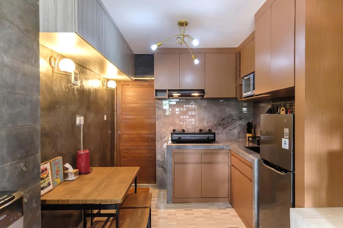 Una cocina moderna con armarios de madera, un microondas integrado, un refrigerador de acero inoxidable y una estufa a gas.