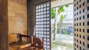 A room with a wooden bench, a wooden table, and a view of the street outside through a glass door. - Jasmine Villa by TwoSpaces Jimbaran (Jimbaran)