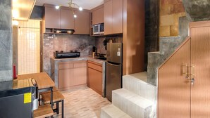 A modern kitchen with wooden cabinets, a built-in microwave, a stainless steel refrigerator, and a dining area with a table and chairs. - Jasmine Villa by TwoSpaces Jimbaran (Jimbaran)
