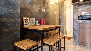 A kitchen with a wooden table and stools, a red mug, and two framed signs on the wall. - Jasmine Villa by TwoSpaces Jimbaran (Jimbaran)