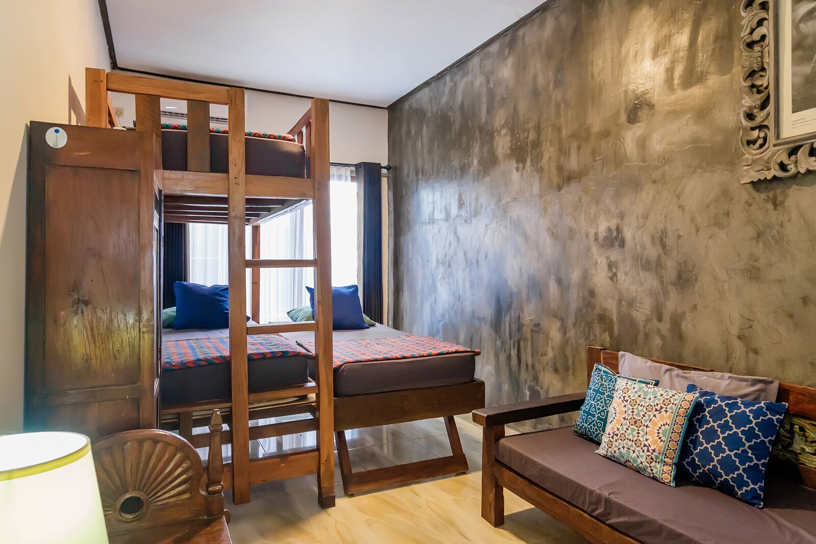 A room with a bunk bed, a sofa, and a wooden chair.