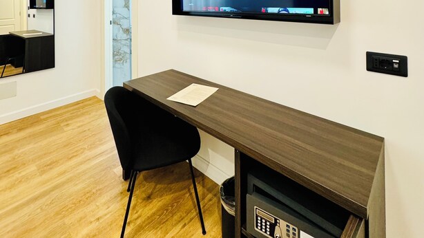 A modern office space with a desk, chair, and a mounted TV displaying a cloud interface. - Museum Hospitality - Vatican Apartments (Rome)