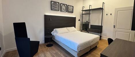 A modern bedroom with a bed, bedside tables, a desk, and a shelving unit.