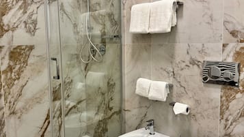 Un baño moderno con ducha envuelta en vidrio, un bidé y un inodoro.