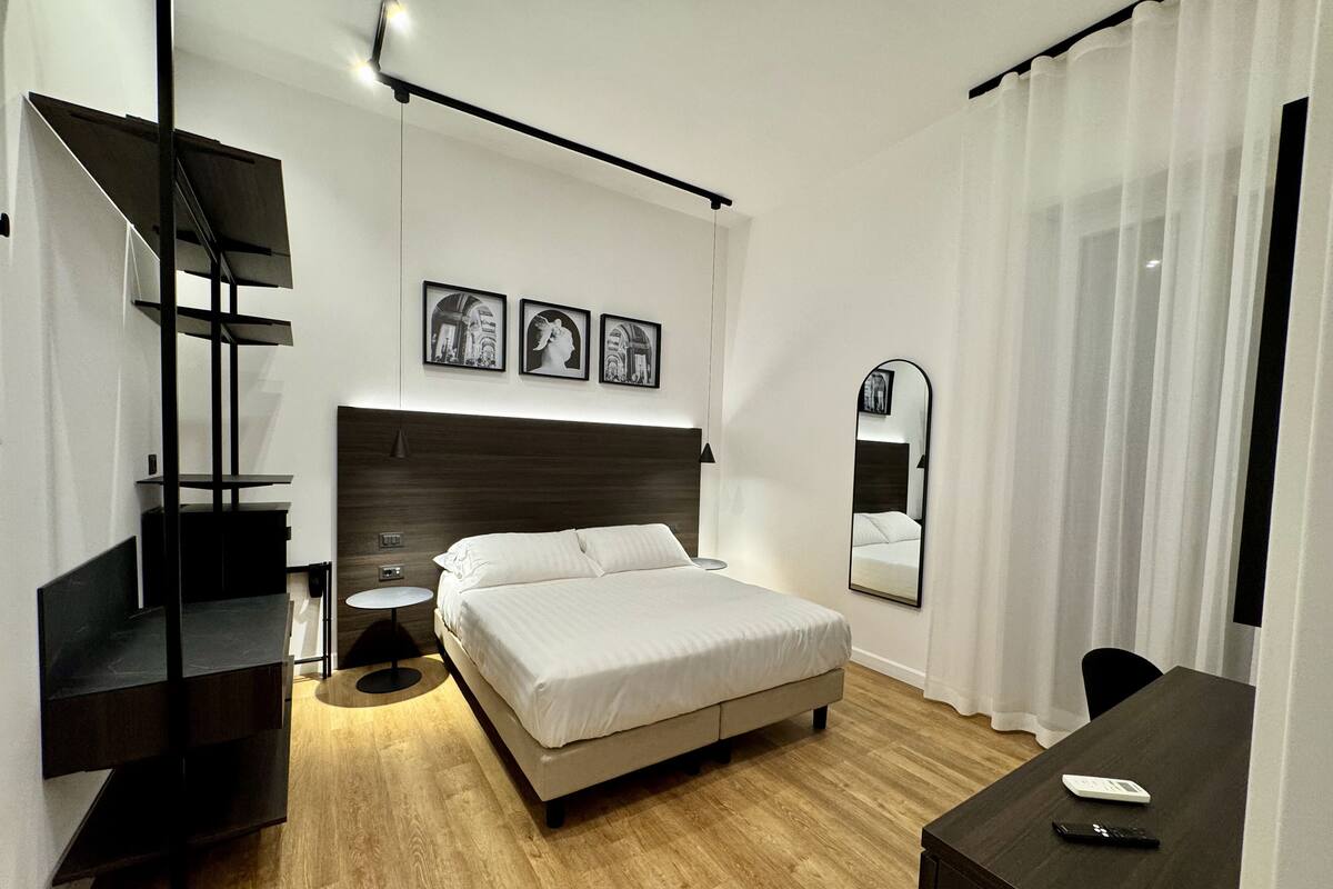 A modern bedroom with a bed, bedside table, and a desk.