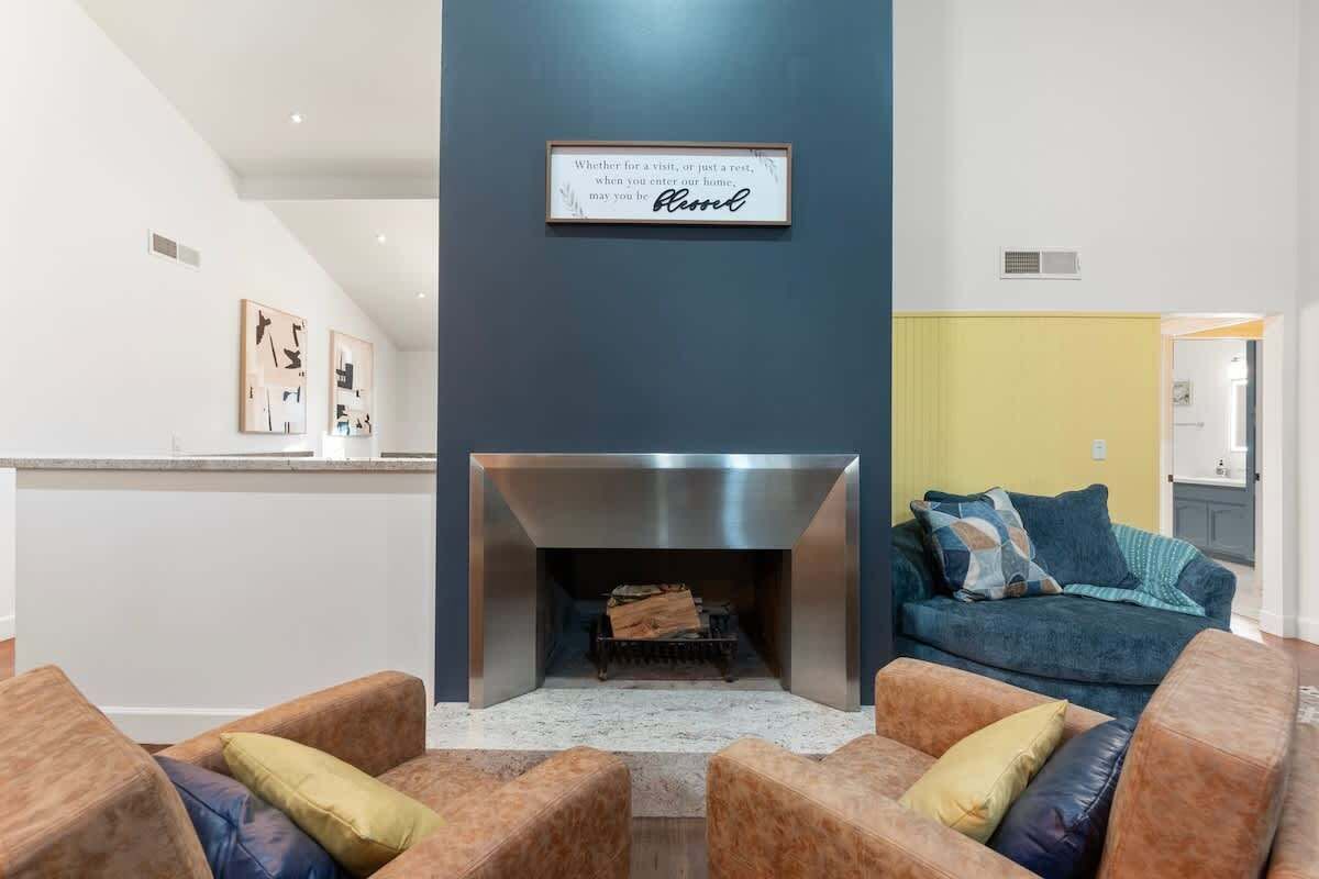 A modern living room with a fireplace, a couch, and a framed sign above it.