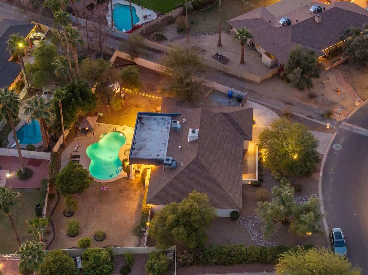 An aerial view of a residential area with a swimming pool, a covered patio, and a street.