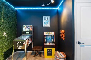 Une pièce avec deux bornes d’arcade, une affiche encadrée et une porte.