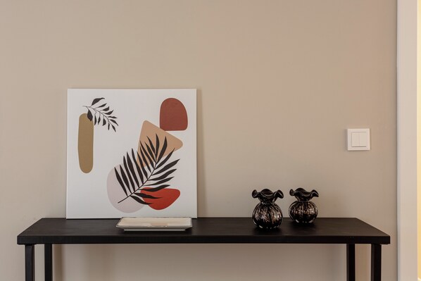 A framed artwork on a black table against a beige wall.