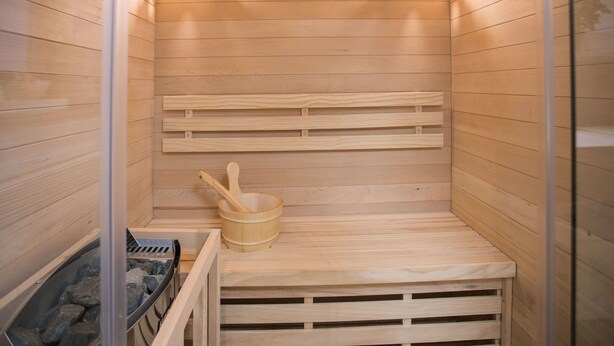 En sauna med træbænke, en træspand og en saunaovn.