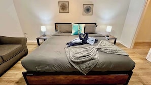 A bedroom with a large bed, two bedside tables, a nightstand, a sofa, and two wall-mounted lamps. - family Spacious Heated Pool Home 5 Min To Weeki Wachee (Spring Hill)