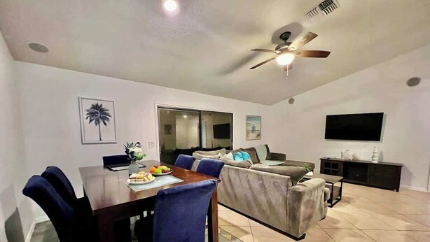A dining area with a table, chairs, and a TV in the background. - family Spacious Heated Pool Home 5 Min To Weeki Wachee (Spring Hill)