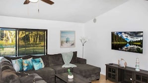 A living room with a dark grey sofa, a coffee table, and a cabinet with decorative items. - family Spacious Heated Pool Home 5 Min To Weeki Wachee (Spring Hill)