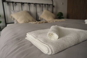 A neatly made bed with a folded white towel on top. - Luxury Prague Apartment in Heart of City (Prague)