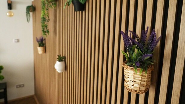 A room with a wooden slat wall, various potted plants, and a hanging basket with purple flowers. - Luxury Prague Apartment in Heart of City (Prague)
