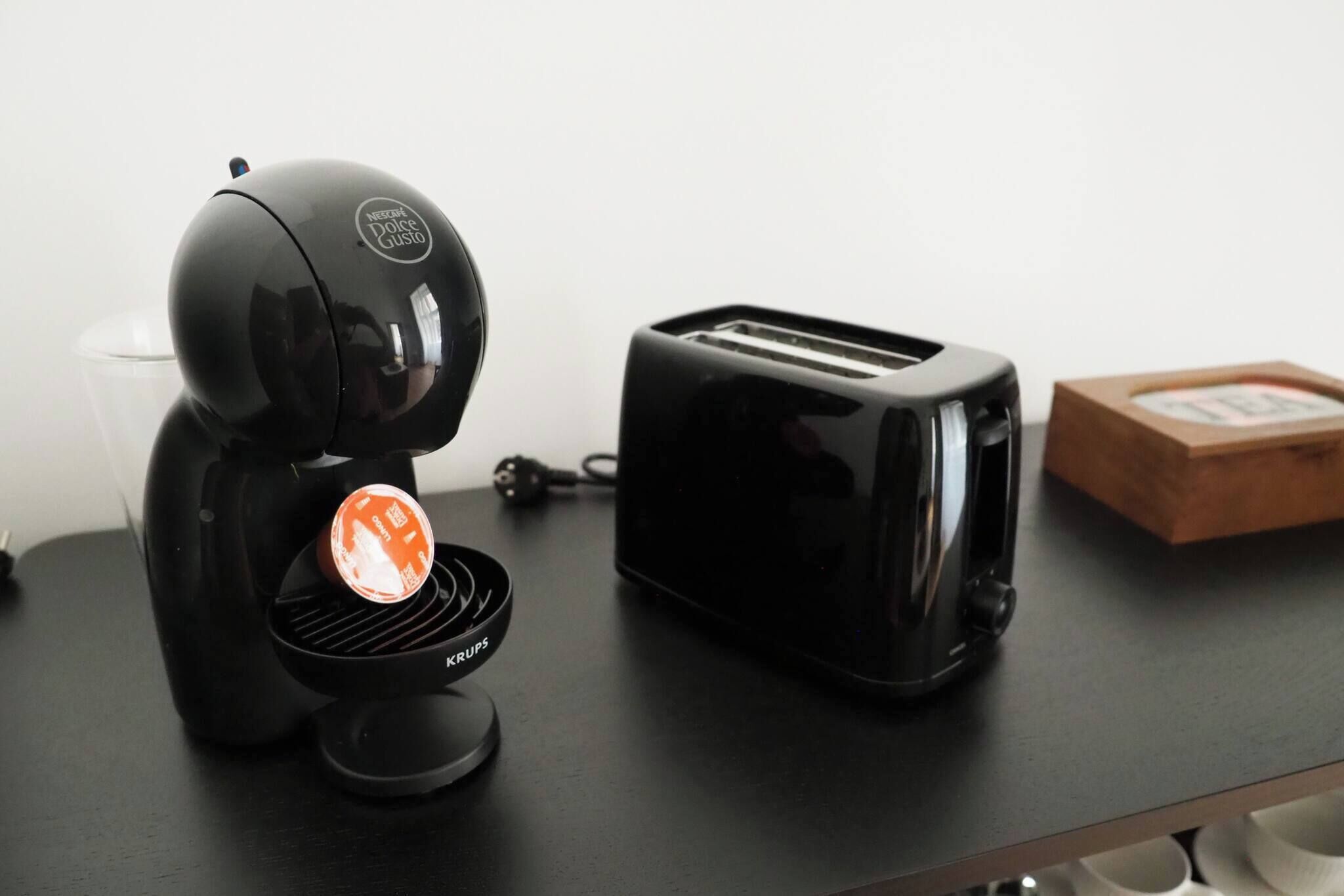 A black coffee maker with a visible brand logo and a toaster on a black countertop.