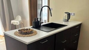 A modern kitchen with a black sink, a kettle, and a small dish of dried fruits on the counter. - Luxury Prague Apartment in Heart of City (Prague)