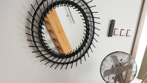 A wooden desk with a black chair, a wall-mounted circular mirror, a standing fan, and a wooden floor. - Luxury Prague Apartment in Heart of City (Prague)