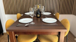 A dining table set with white plates, cutlery, and glasses, with a bottle of champagne in the center. - Luxury Prague Apartment in Heart of City (Prague)
