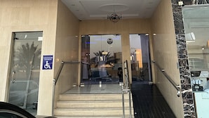 The entrance to the Ajnahat Albidaah Hotel with a marble facade and a sign in Arabic.