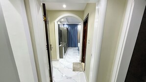 A hallway with a marble floor leading to a room with a blue curtain.