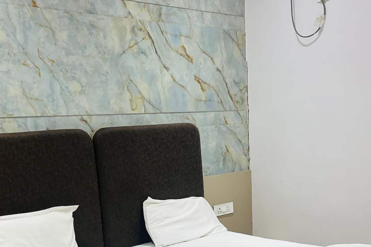 Una habitación de hotel moderna con pared con diseño de mármol, una cama grande con ropa blanca y un equipo de aire acondicionado instalado en la pared.