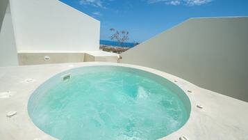 Un moderno jacuzzi al aire libre con vistas despejadas al mar y un árbol de fondo.