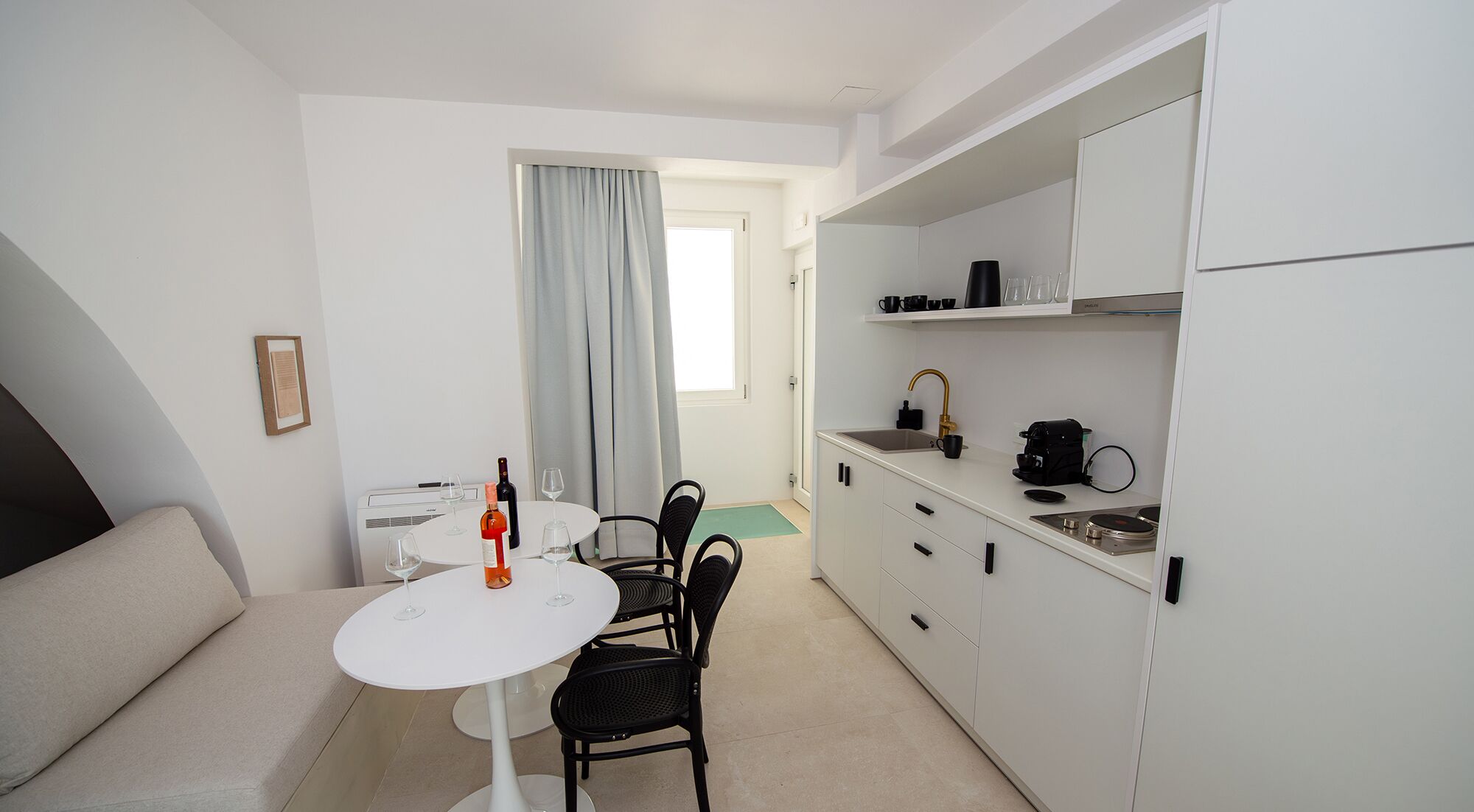 Una kitchenette compacta con un lavamanos, una cafetera y un refrigerador pequeño.