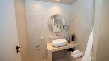 A bathroom with a round mirror, a sink, and a towel rack.