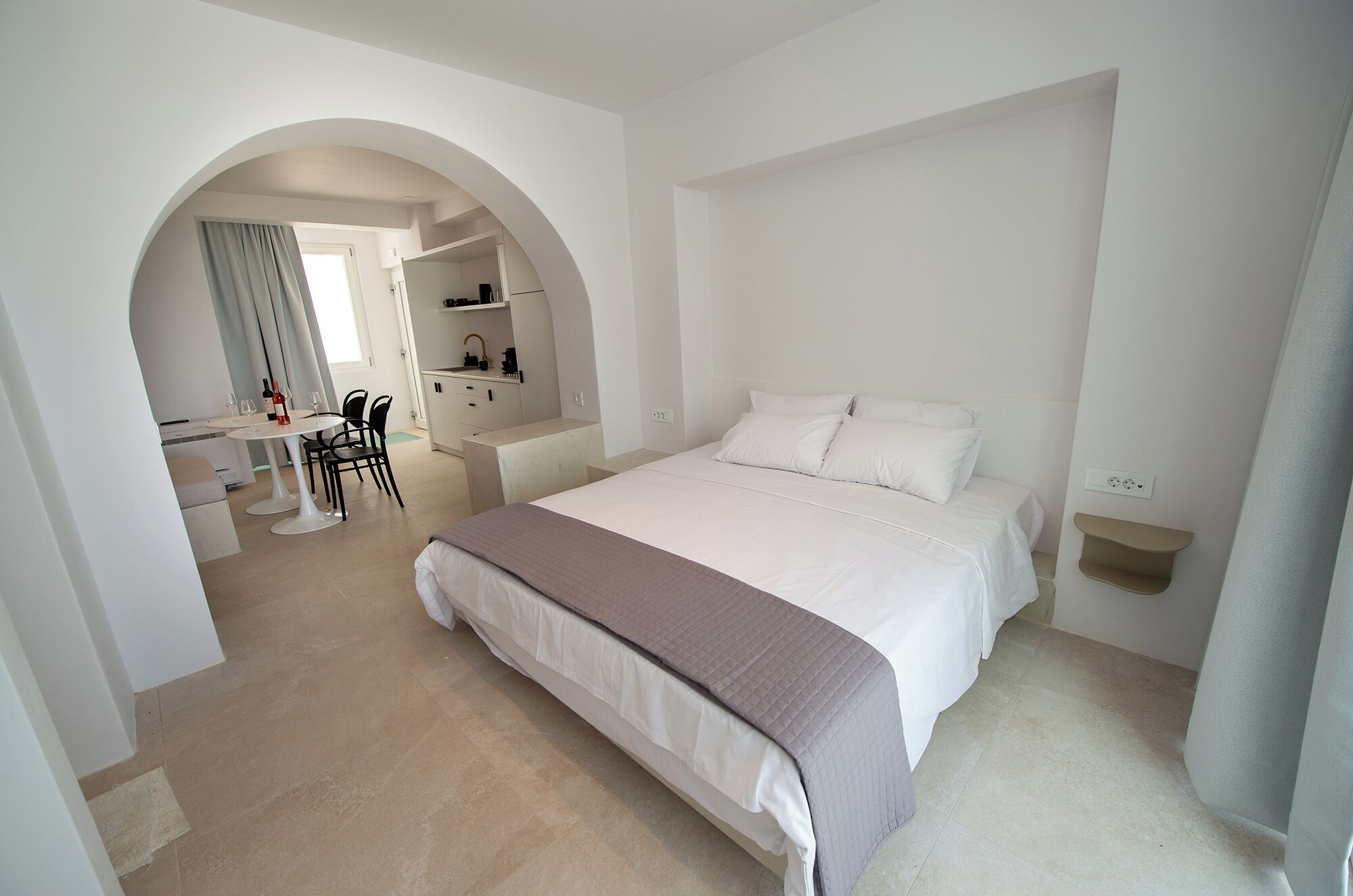 Un dormitorio con una cama grande, un escritorio con sillas y una kitchenette.