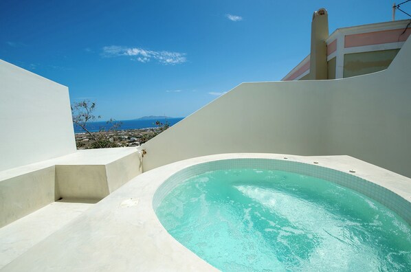 A modern outdoor swimming pool with a clear view of the sea and distant land. - Atria Suites  (Santorini)