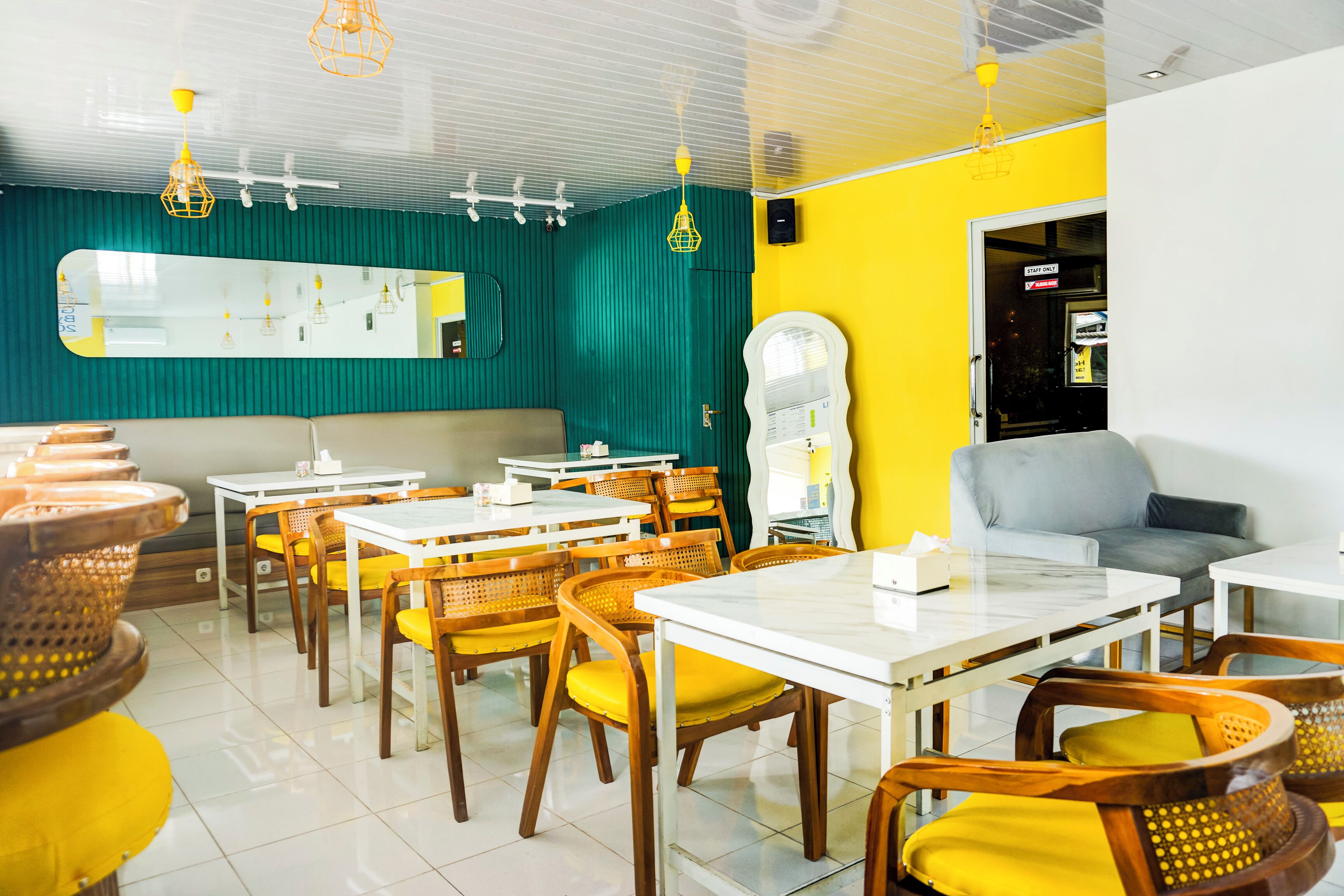 Un restaurante con sillas y mesas de madera, un espejo y una pared amarilla.