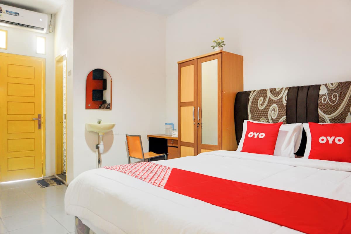 Ein Hotelzimmer mit einem Bett, einem Schrank, einem Schreibtisch mit Stuhl und einem Spiegel an der Wand.
