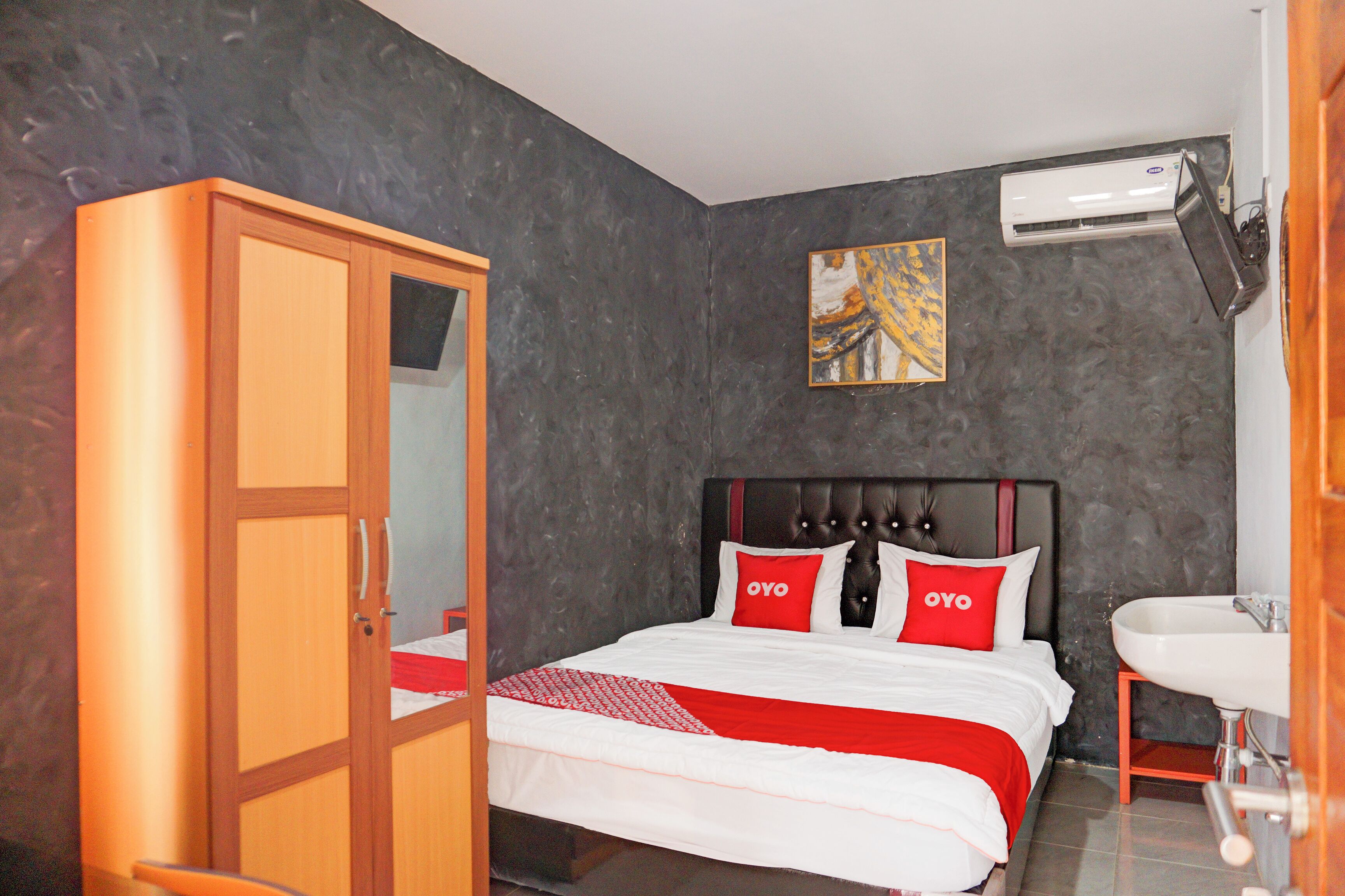 A hotel room with a bed, a wardrobe, a painting, and a bathroom.