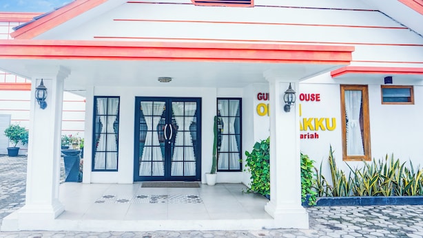 A hotel entrance with a white facade, red roof, and black-framed windows. - Hotel O Bandar Lampung Near Gor Saburai Formerly Omah Anakku (Bandar Lampung)