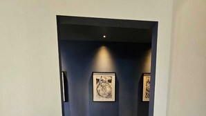 Un pasillo con pared oscura, una obra de arte enmarcada y suelo de madera.