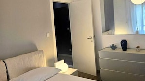 Una habitación de hotel moderna con cama, cómoda, espejo y lámpara redonda.