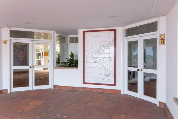 A lobby with glass doors, a large abstract art piece, and a tiled floor. - Kandinsky apartment with sea view (L'Escala)
