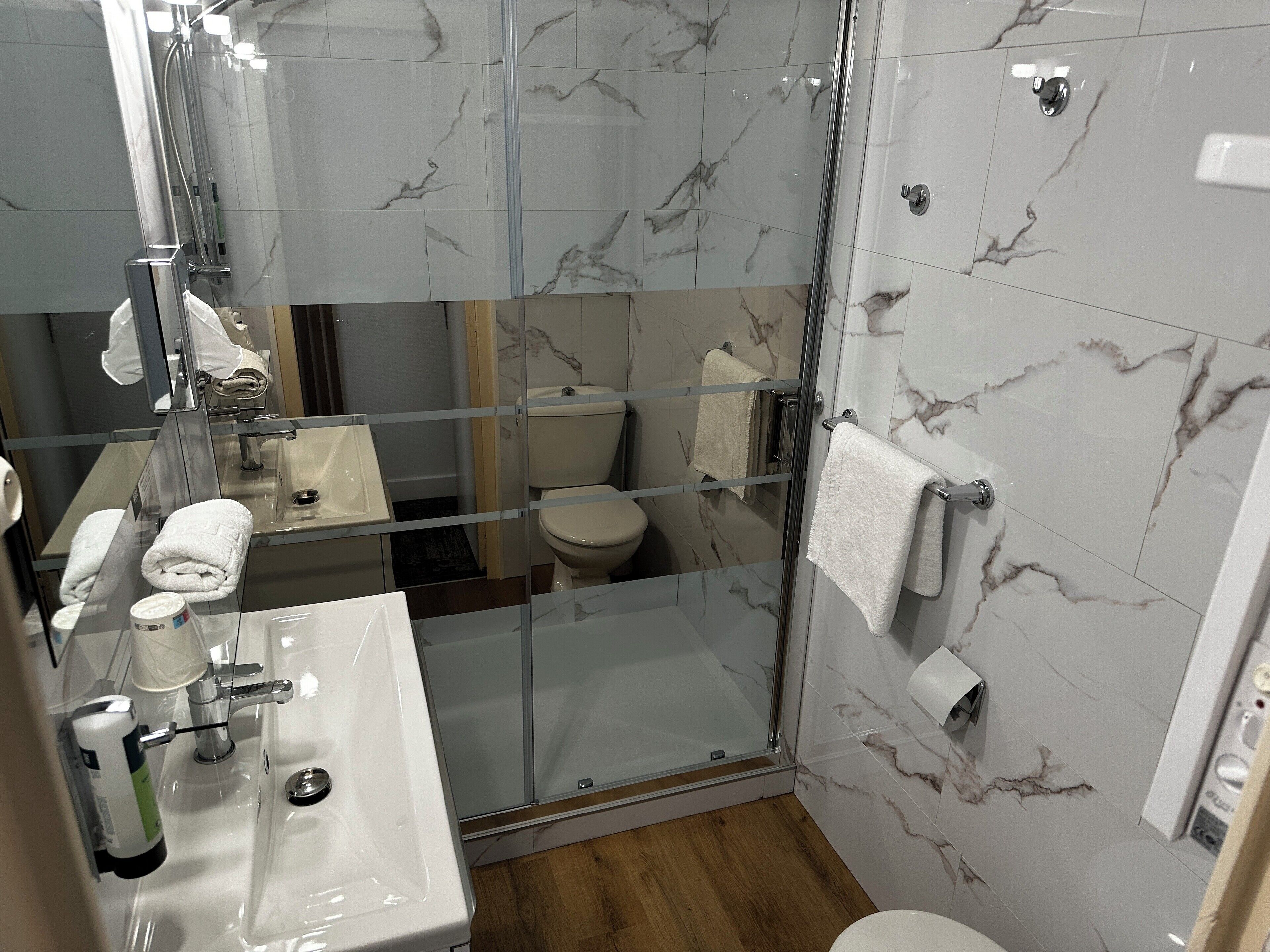 Ein modernes Badezimmer mit einer Duschkabine, einem Waschbecken mit Seifenspender und einer Toilette.